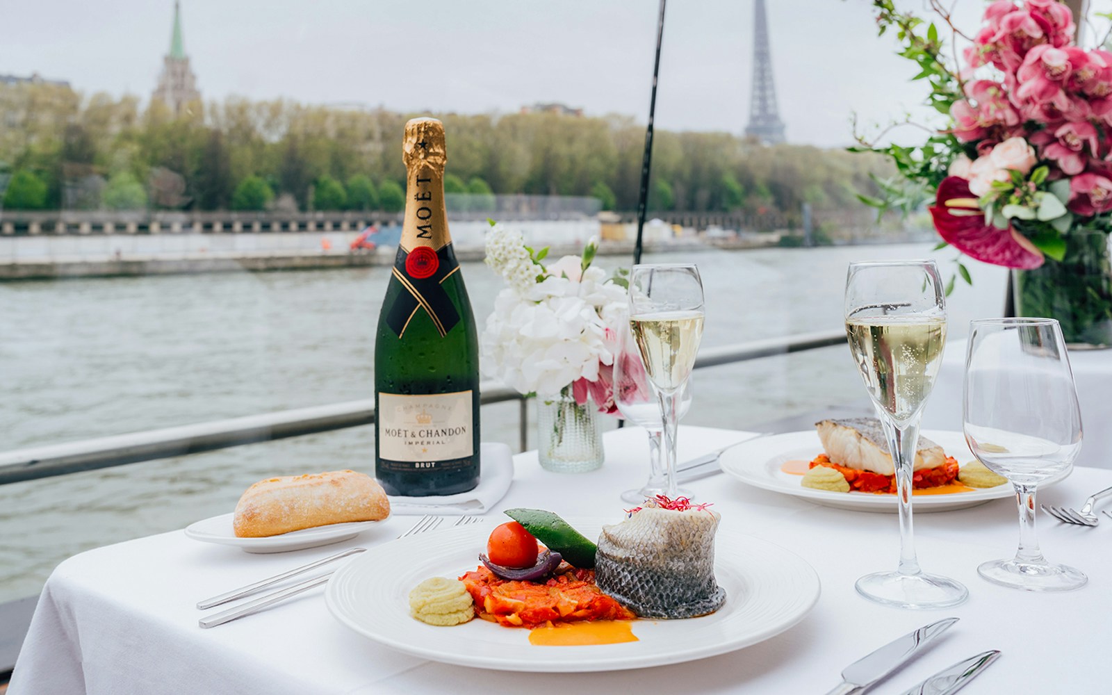 Seine River cruise boat with passengers enjoying champagne near Eiffel Tower, Paris.