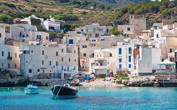 Levanzo town on Egadi Island with white buildings and boats in turquoise water.