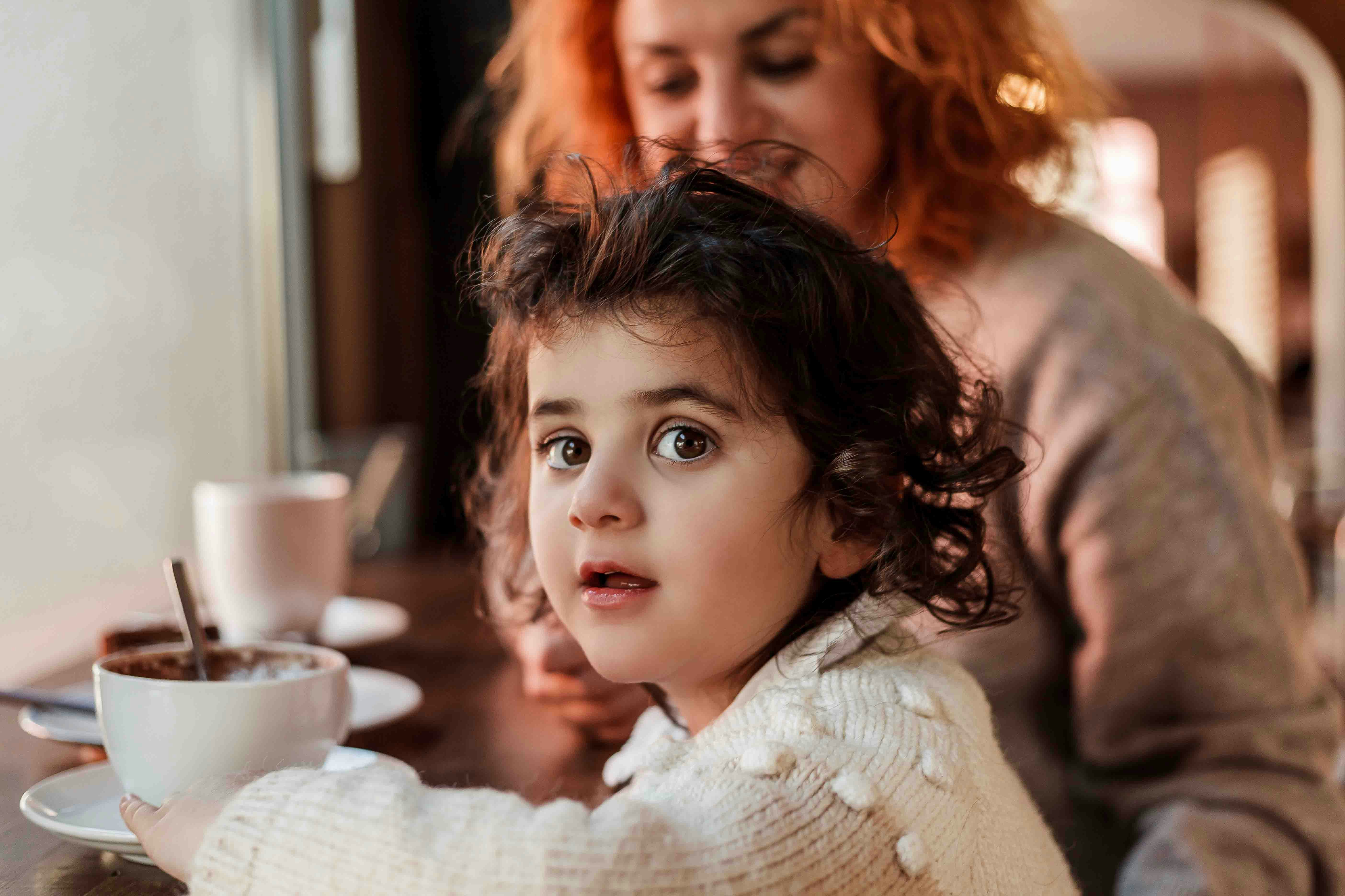 Child sitting at a table with a cup of hot chocolate at The Edge NYC bar.