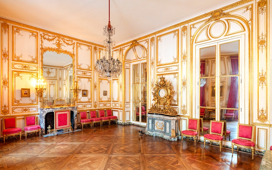 Versailles Palace King's Private Apartments with ornate gold decor and red chairs.