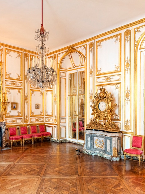 Versailles Palace King's Private Apartments with ornate gold decor and red chairs.
