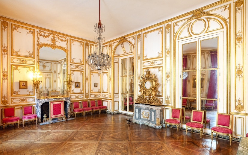 Versailles Palace King's Private Apartments with ornate gold decor and red chairs.