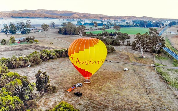 Hot air balloon over scenic Australian landscape, part of a luxury experience for two.