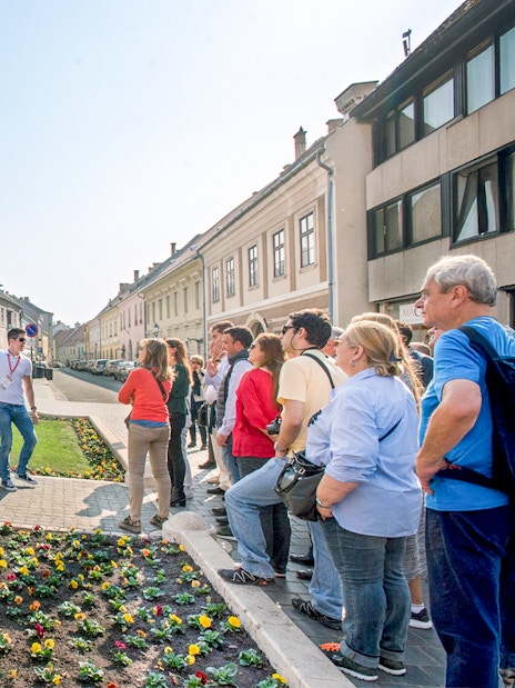 Tour group with guide at equestrian statue in Budapest.