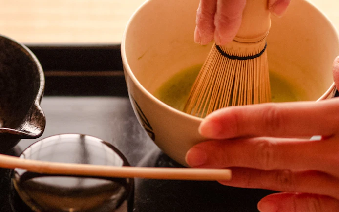 Whisking matcha tea in a bowl during a tea ceremony in Kyoto Karasuma Area.