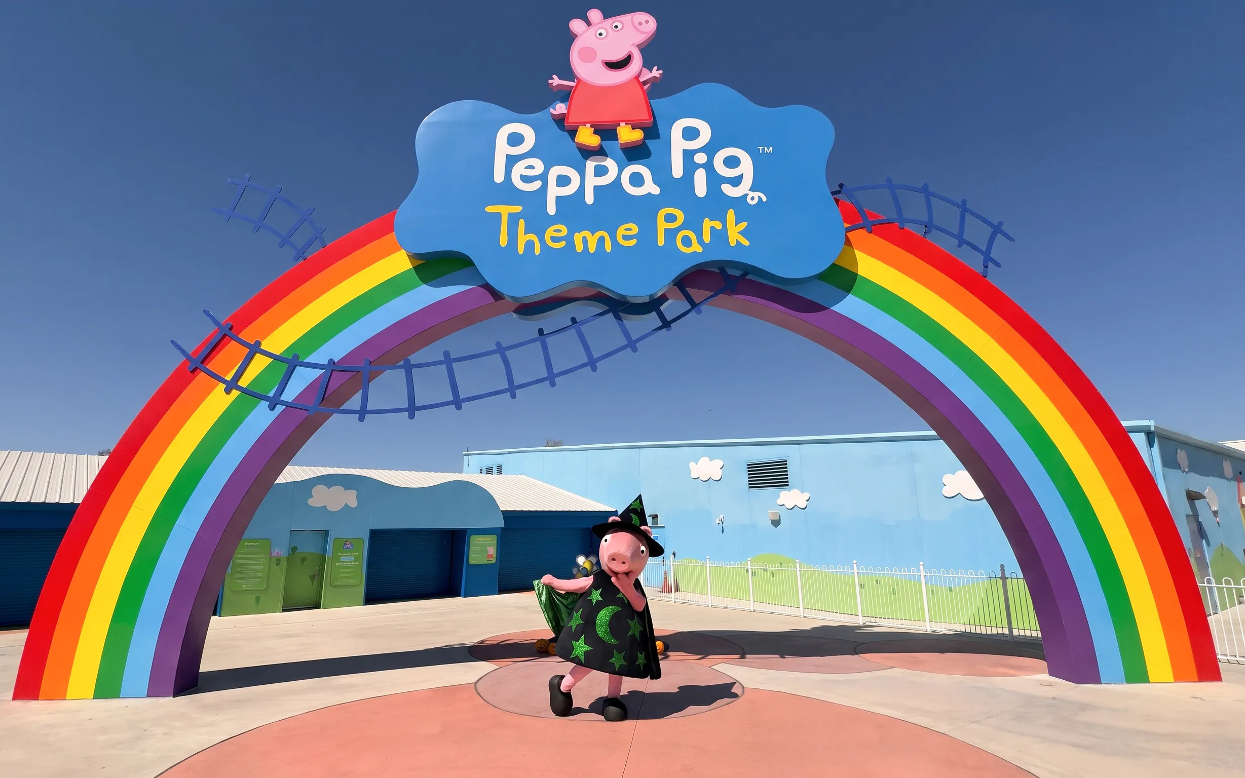 Peppa Pig in Halloween costume under rainbow arch at Peppa Pig Theme Park, Florida.