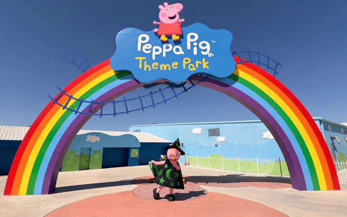 Peppa Pig in Halloween costume under rainbow arch at Peppa Pig Theme Park, Florida.