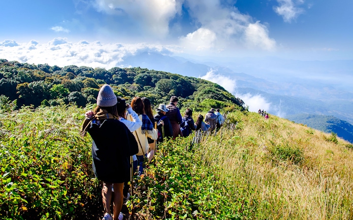 Group trekking at sunrise on Kew Mae Parn trail, Inthanon National Park, Thailand.