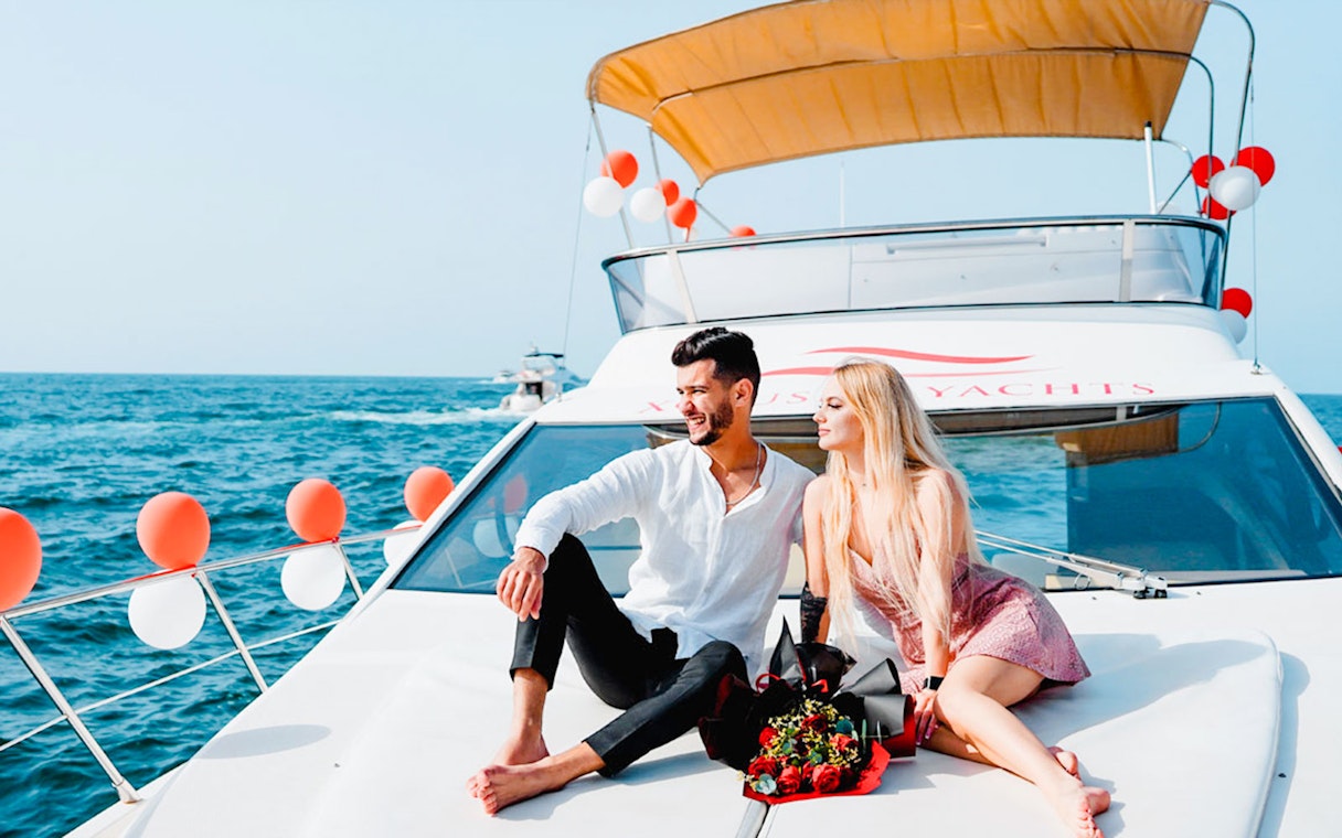 Couple relaxing on a luxury private yacht in Dubai with a bouquet of roses.