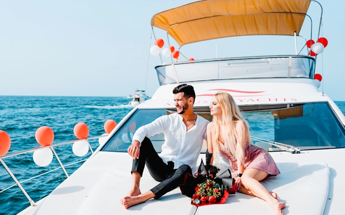 Couple relaxing on a luxury private yacht in Dubai with a bouquet of roses.