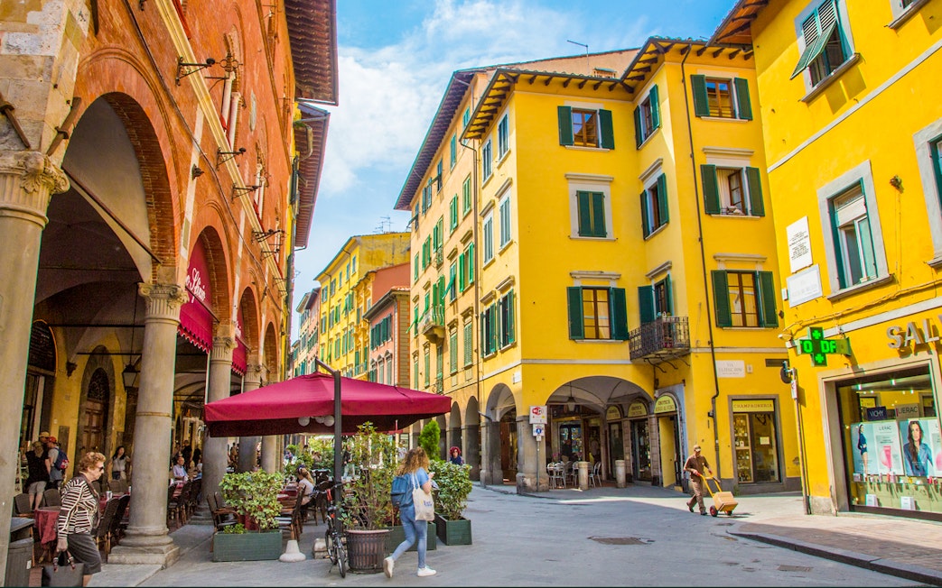 Street view of colorful buildings and outdoor cafes in Pisa during a guided walking tour.