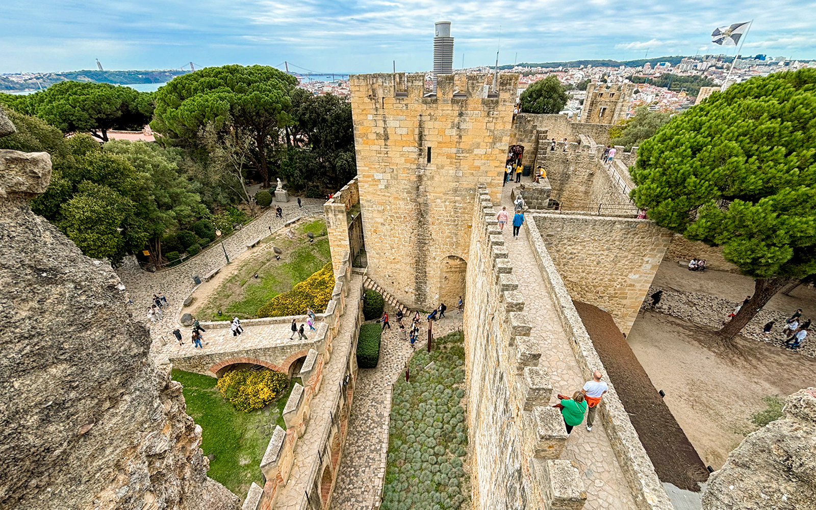 Top view of São Jorge Castle's entrance bridge with visitors walking along the stone path in Lisbon.