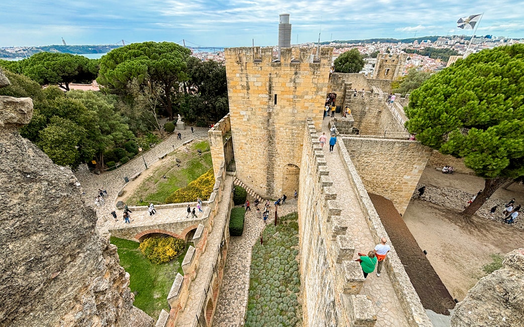 Top view of São Jorge Castle's entrance bridge with visitors walking along the stone path in Lisbon.