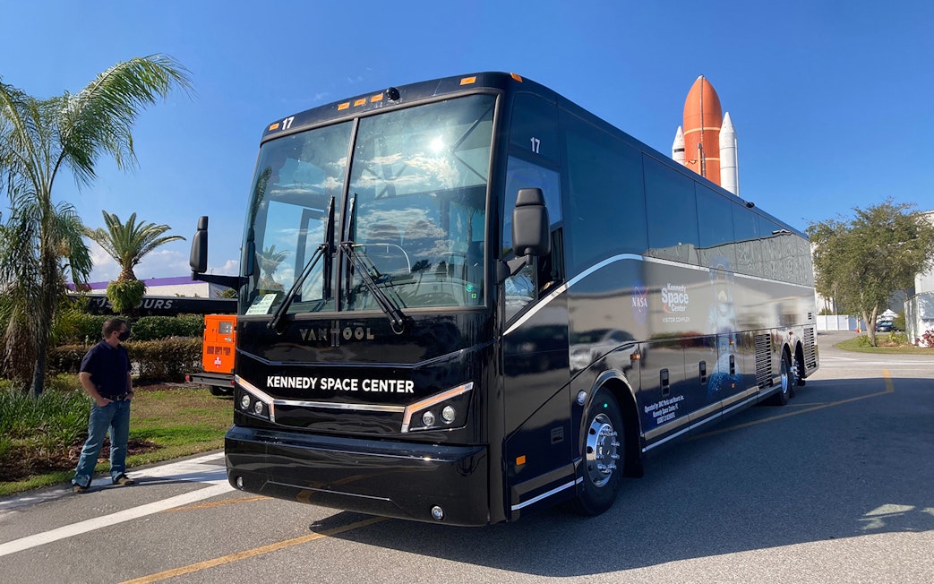 Kennedy Space Center tour bus parked near space shuttle exhibit.