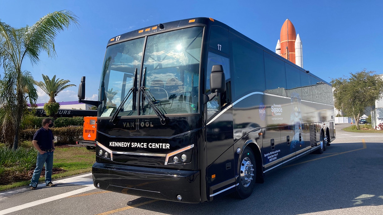 Kennedy Space Center tour bus parked near space shuttle exhibit.