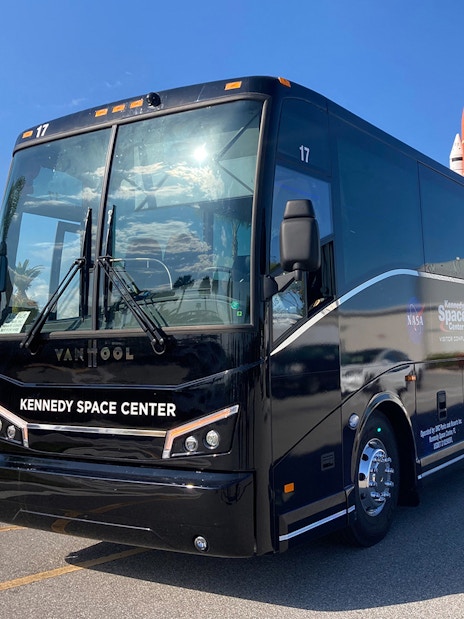 Kennedy Space Center tour bus parked near space shuttle exhibit.