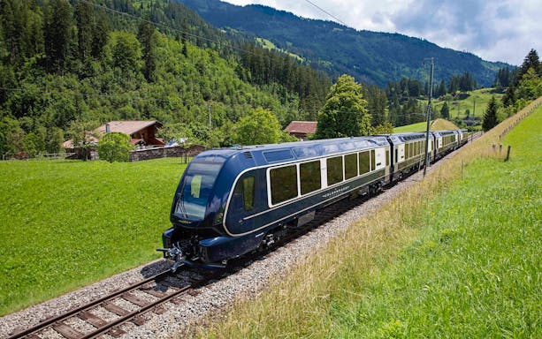 GoldenPass Express train traveling through lush Swiss countryside.
