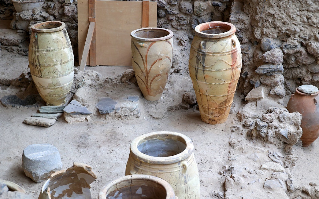 Amphorae at Akrotiri Archaeological Site, Santorini, Greece, displayed among ancient ruins.