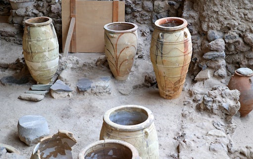 Amphorae at Akrotiri Archaeological Site, Santorini, Greece, displayed among ancient ruins.