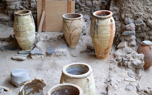 Amphorae at Akrotiri Archaeological Site, Santorini, Greece, displayed among ancient ruins.