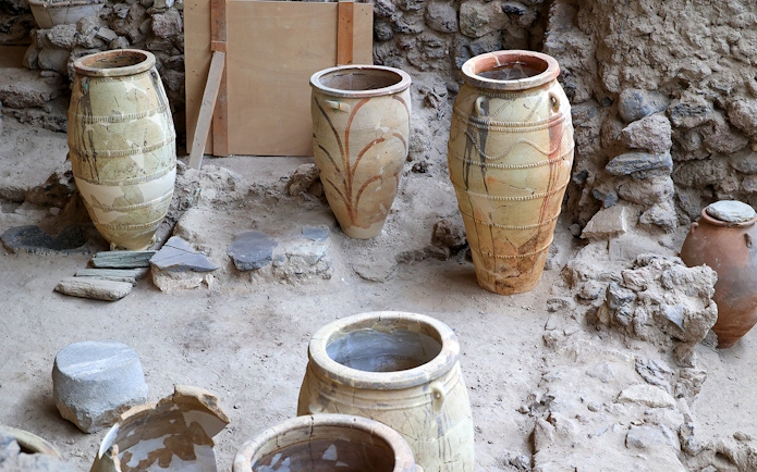 Amphorae at Akrotiri Archaeological Site, Santorini, Greece, displayed among ancient ruins.