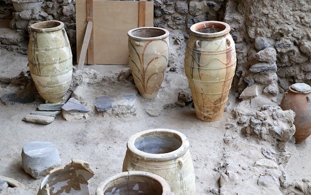 Amphorae at Akrotiri Archaeological Site, Santorini, Greece, displayed among ancient ruins.