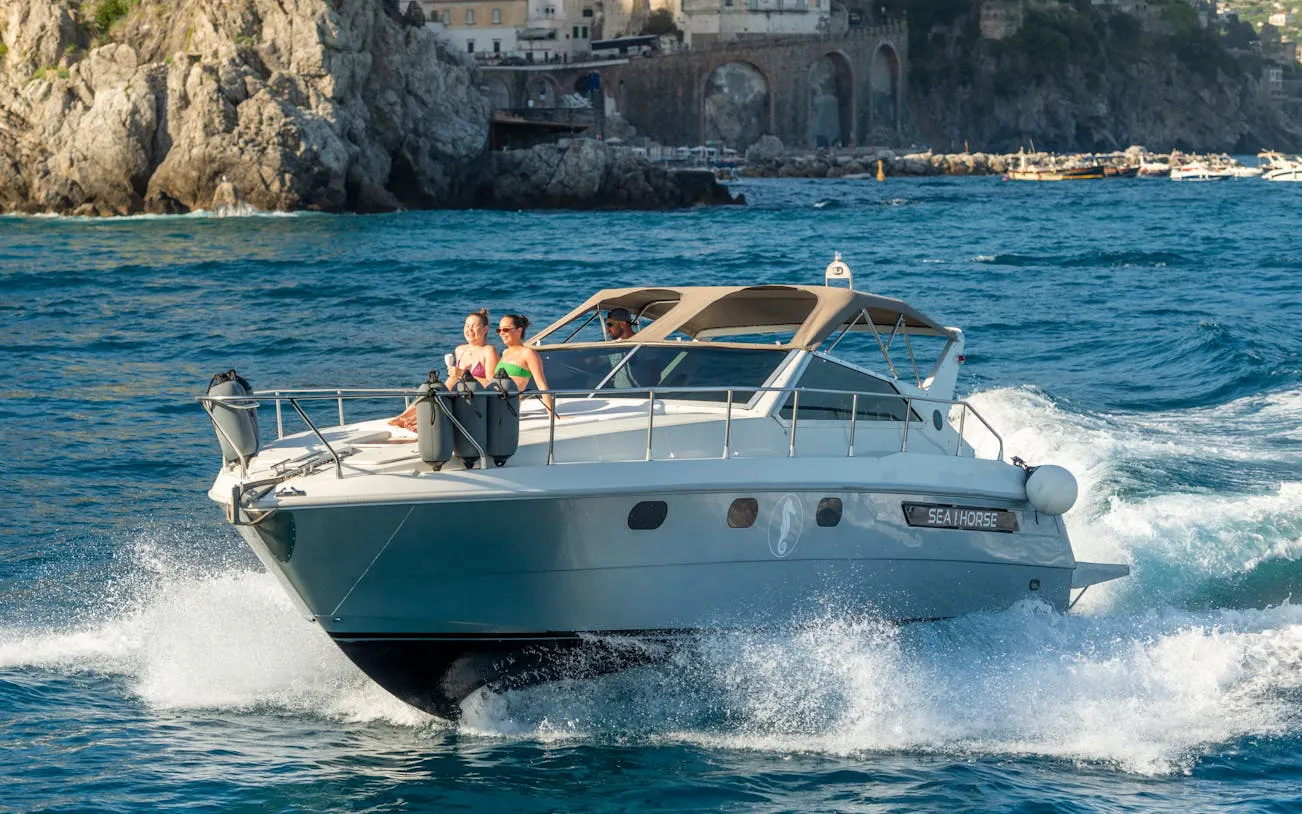 Luxury boat sailing from Amalfi to Positano with passengers enjoying Prosecco.