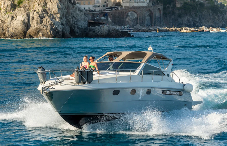 Luxury boat sailing from Amalfi to Positano with passengers enjoying Prosecco.
