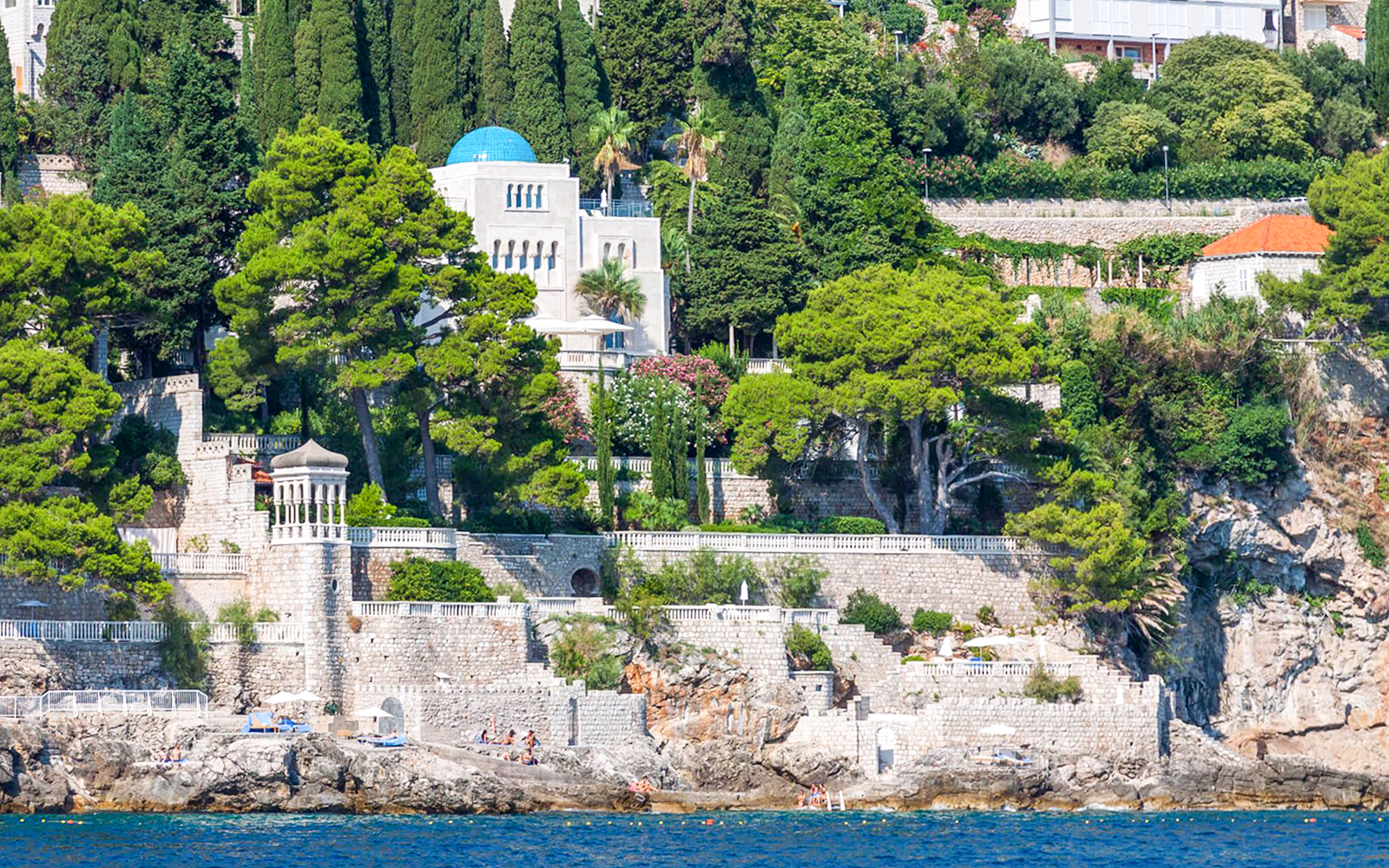 Seaside view of Dubrovnik's lush coastline, featuring stone walls and greenery, seen on Game of Thrones boat tour.