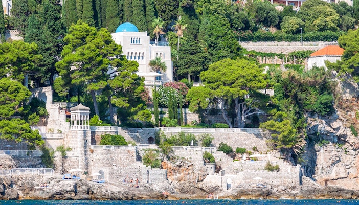Seaside view of Dubrovnik's lush coastline, featuring stone walls and greenery, seen on Game of Thrones boat tour.