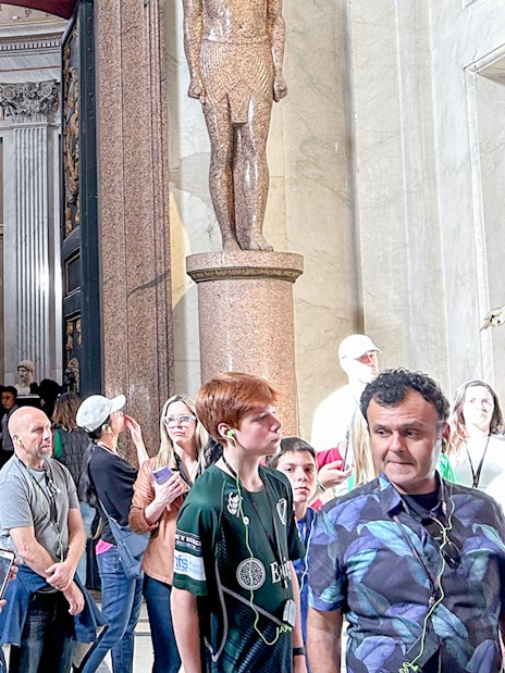 Visitors exploring the Vatican Museums entrance with statues and ornate doorway.