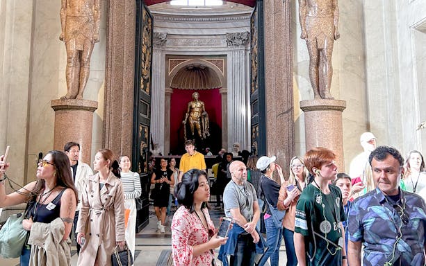 Visitors exploring the Vatican Museums entrance with statues and ornate doorway.