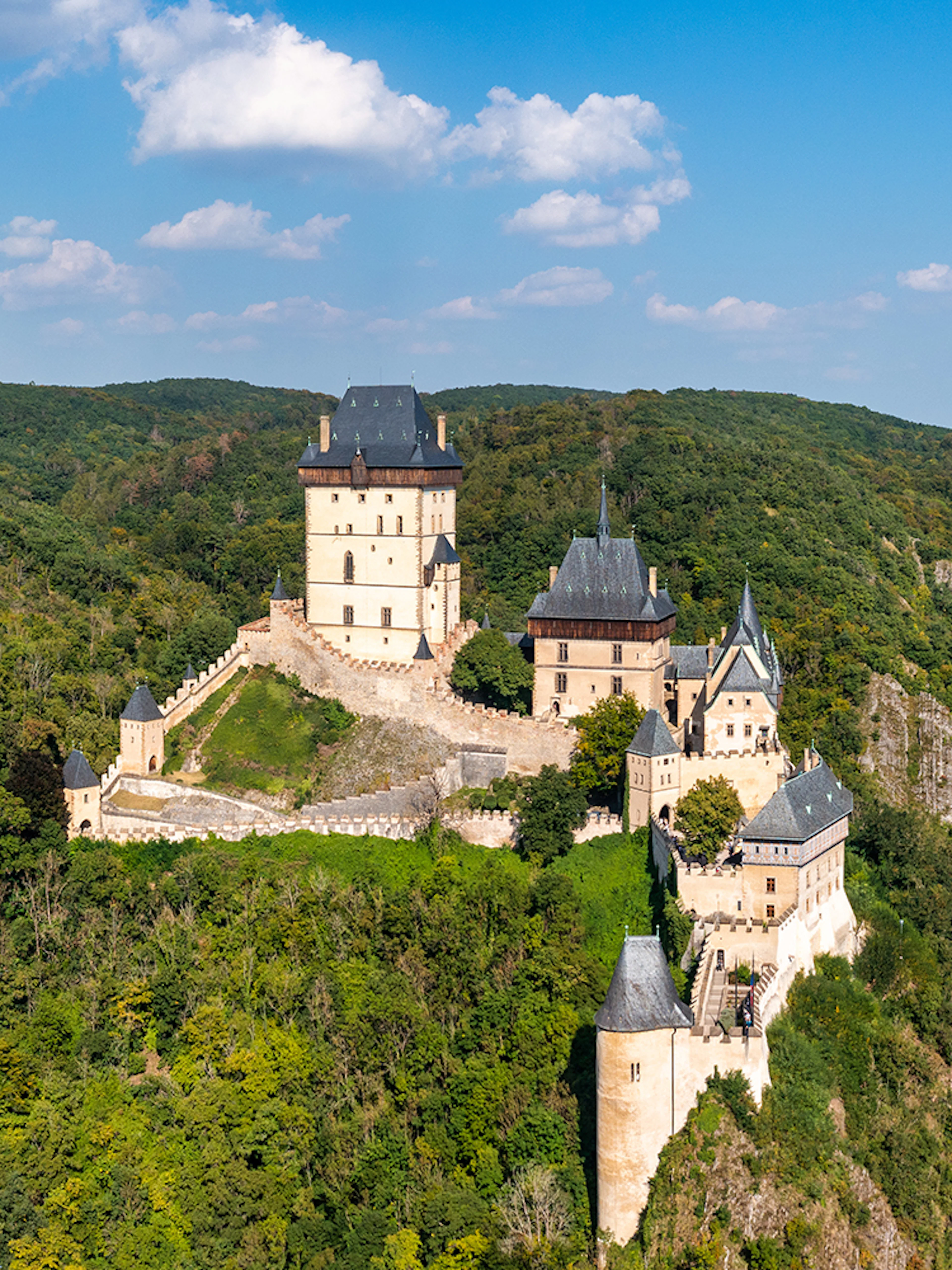 Aerial view of Karlštejn Castle's Great Tower surrounded by lush forest in the Czech Republic.