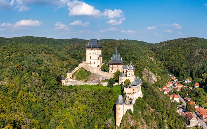 Aerial view of Karlštejn Castle's Great Tower surrounded by lush forest in the Czech Republic.