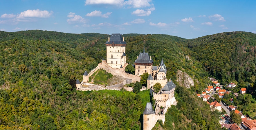 Aerial view of Karlštejn Castle's Great Tower surrounded by lush forest in the Czech Republic.