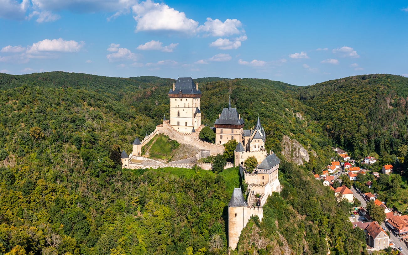 Aerial view of Karlštejn Castle's Great Tower surrounded by lush forest in the Czech Republic.