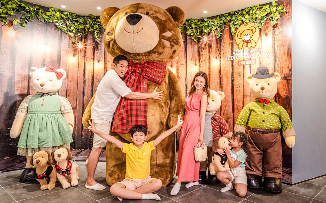 Family posing with large teddy bears at Teddy Bear Museum, Phu Quoc.