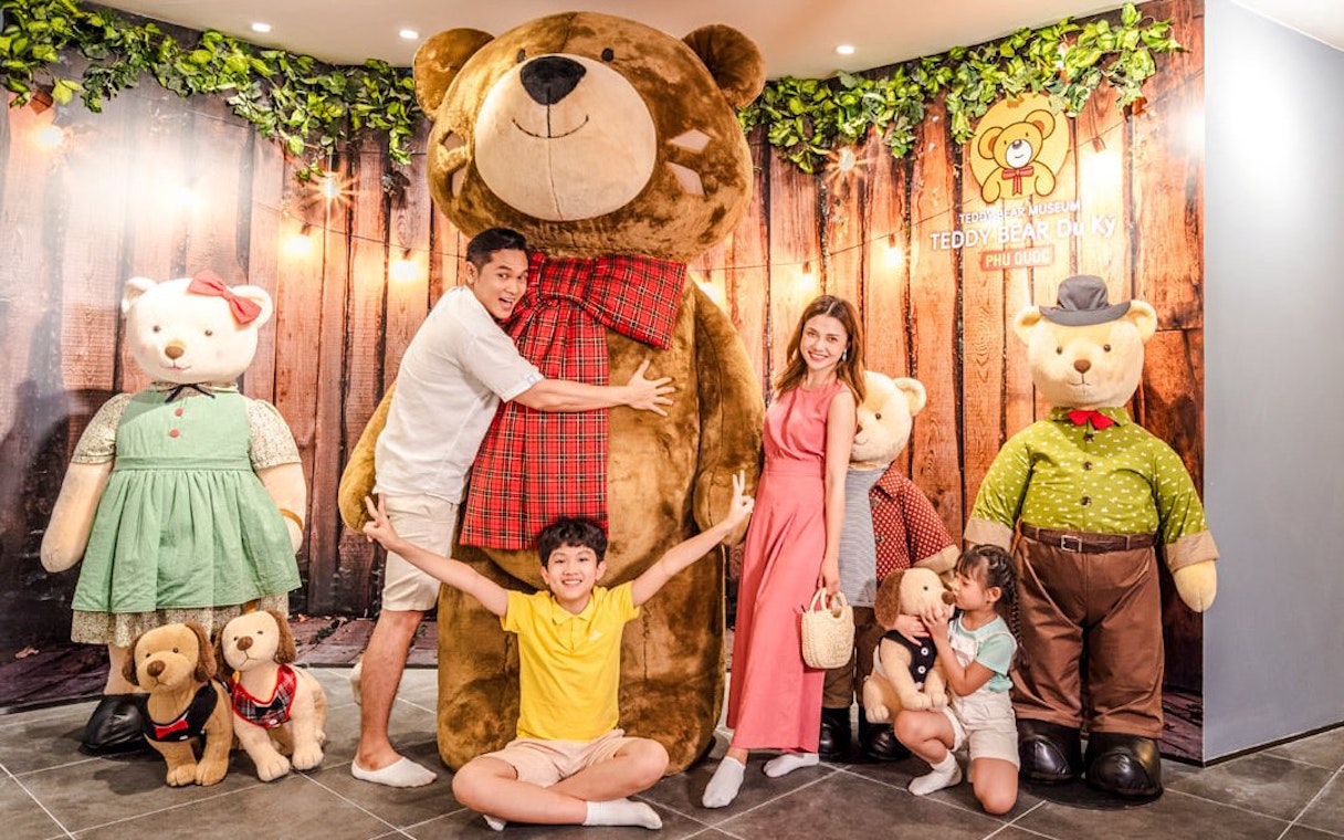 Family posing with large teddy bears at Teddy Bear Museum, Phu Quoc.