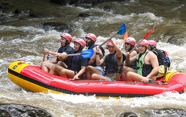Tourists rafting on Ayung River in Bali, navigating rapids with paddles.