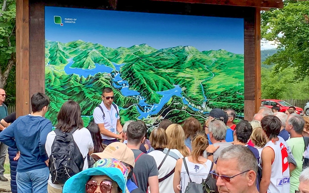 Tour guide explaining map to visitors at Plitvice Lakes, Croatia.