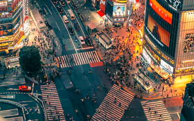 Aerial view of Shibuya Crossing from Shibuya Sky Deck, Tokyo, with bustling crowds and illuminated buildings.