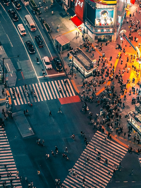 Aerial view of Shibuya Crossing from Shibuya Sky Deck, Tokyo, with bustling crowds and illuminated buildings.