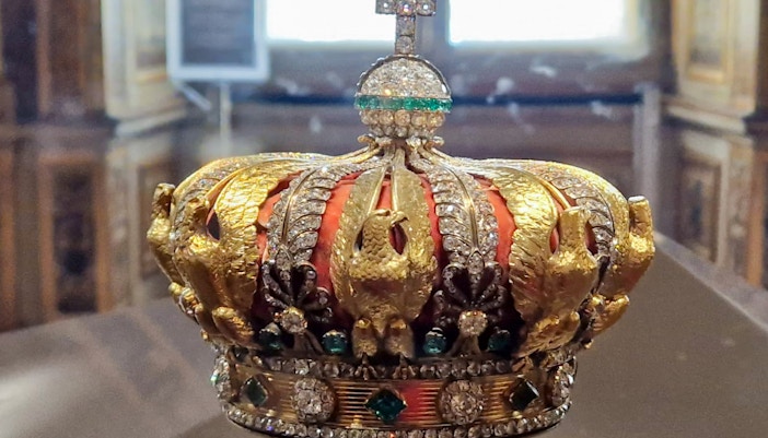 French Crown Jewels display at Louvre Museum, Paris with visitors observing the collection.