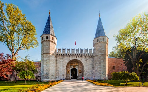 Topkapi Palace entrance with twin towers in Istanbul, Turkey, surrounded by trees.