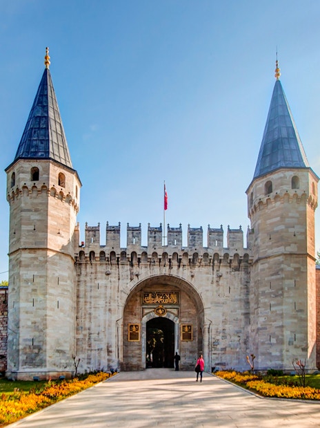 Topkapi Palace entrance with twin towers in Istanbul, Turkey, surrounded by trees.