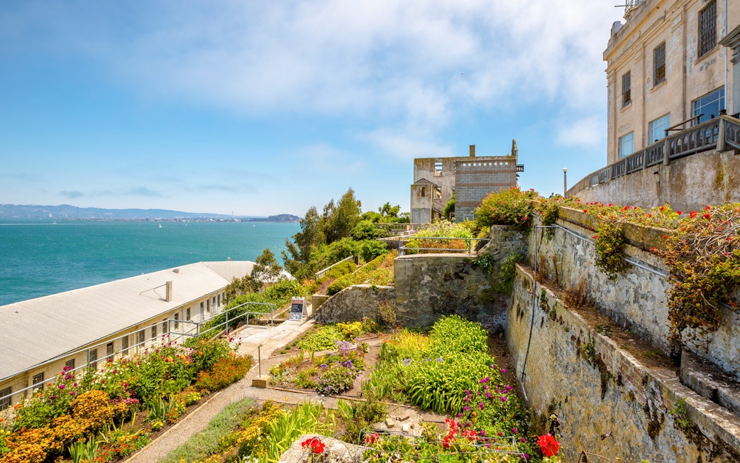 Alcatraz Island garden with historic buildings and view of San Francisco Bay.