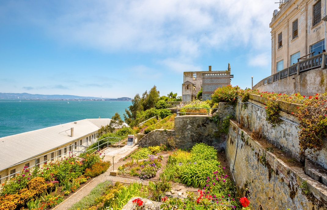 Alcatraz Island garden with historic buildings and view of San Francisco Bay.