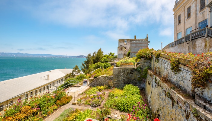 Alcatraz Island garden with historic buildings and view of San Francisco Bay.