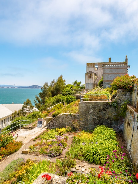 Alcatraz Island garden with historic buildings and view of San Francisco Bay.