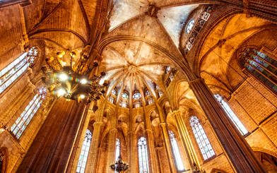 Interior view of the Cathedral of Barcelona's vaulted ceiling and stained glass windows.